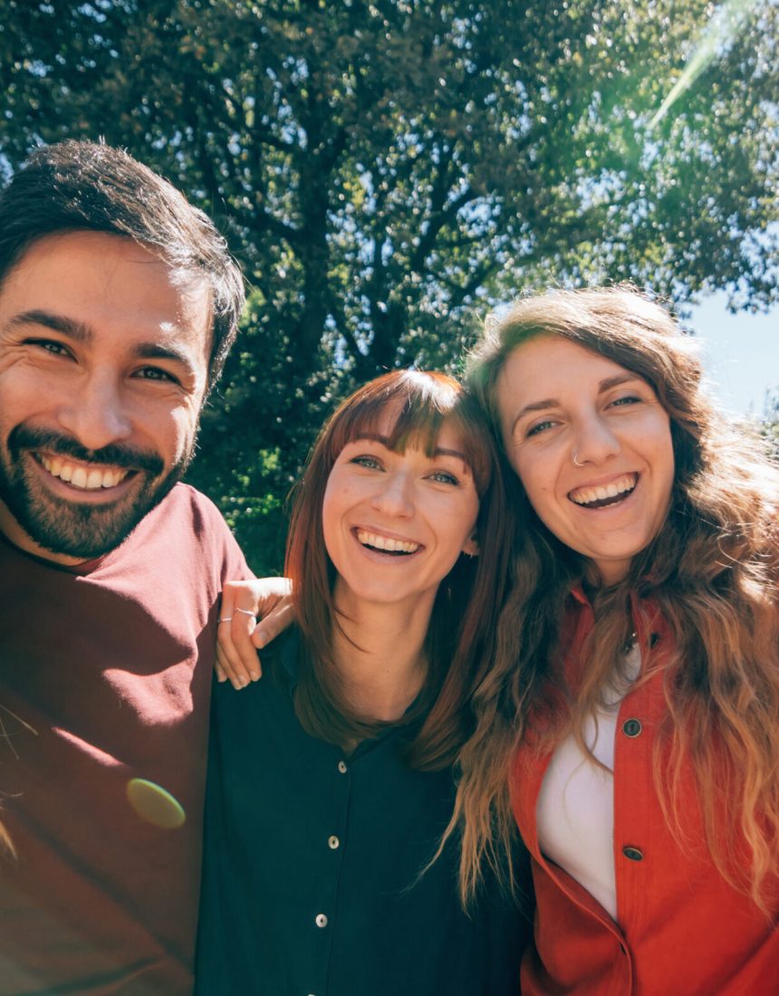 group portrait of smiling positive colorful friends having fun together outdoors in a sunny day - happy friendship concept
