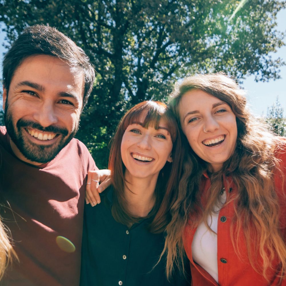 group portrait of smiling positive colorful friends having fun together outdoors in a sunny day - happy friendship concept